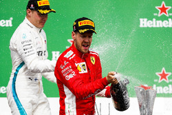 Valtteri Bottas, Mercedes AMG F1, 2nd position, and Sebastian Vettel, Ferrari, 1st position, spray Champagne on the podium