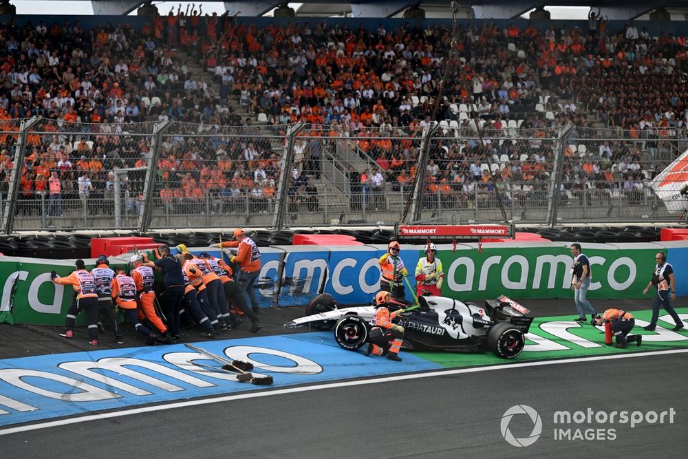 Los oficiales de pista reparan las barreras y asisten el coche dañado de Daniel Ricciardo, AlphaTauri AT04