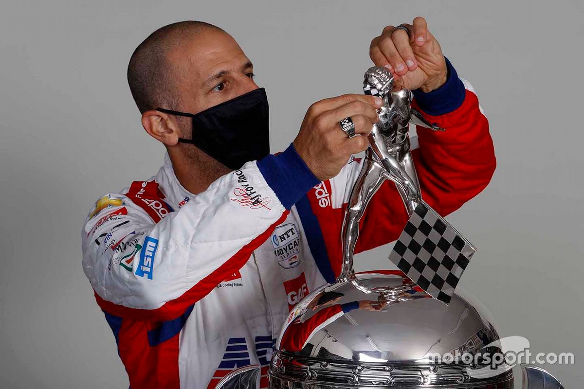 El ganador de la Indy 2013, Tony Kanaan, coloca el cubrebocas al hombrecito del trofeo