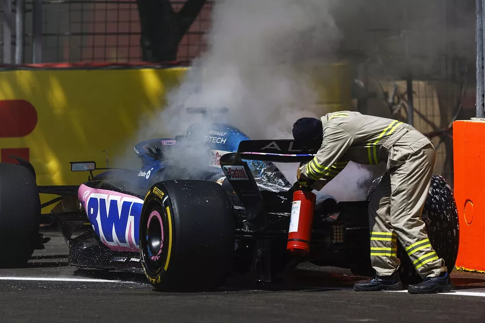 A Marshal uses a fire extinguisher on the car of Pierre Gasly, Alpine A523