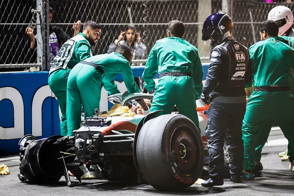Les commissaires et les médecins avec la monoplace détruite de Mick Schumacher, Haas VF-22