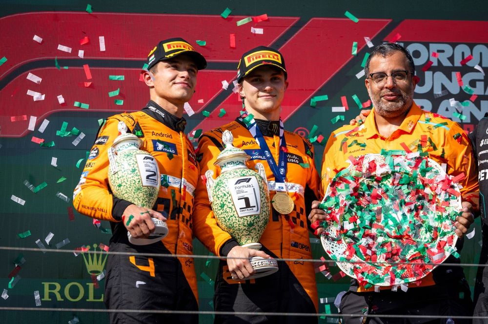 Lando Norris, McLaren F1 Team, 2nd position, Oscar Piastri, McLaren F1 Team, 1st position, and the McLaren trophy delegate with the trophies on the podium