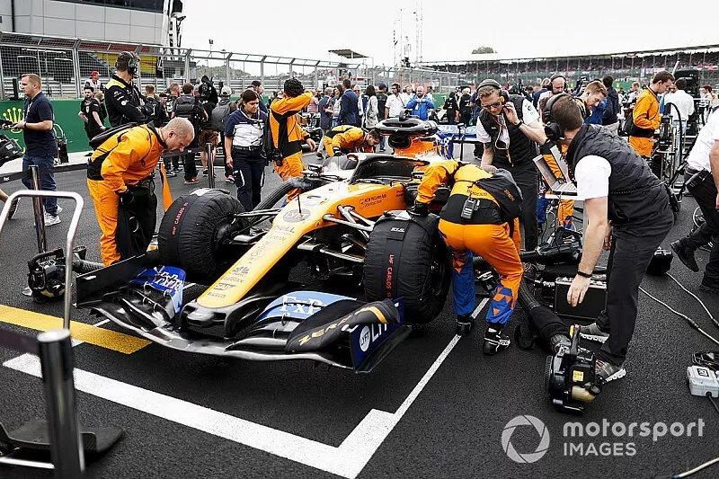 Des m&eacute;caniciens sur la grille avec la voiture de Carlos Sainz Jr., McLaren MCL34