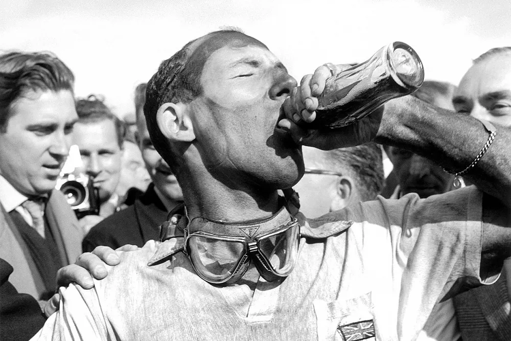 Race winner Stirling Moss, Vanwall  takes a victory drink of Coca-Cola