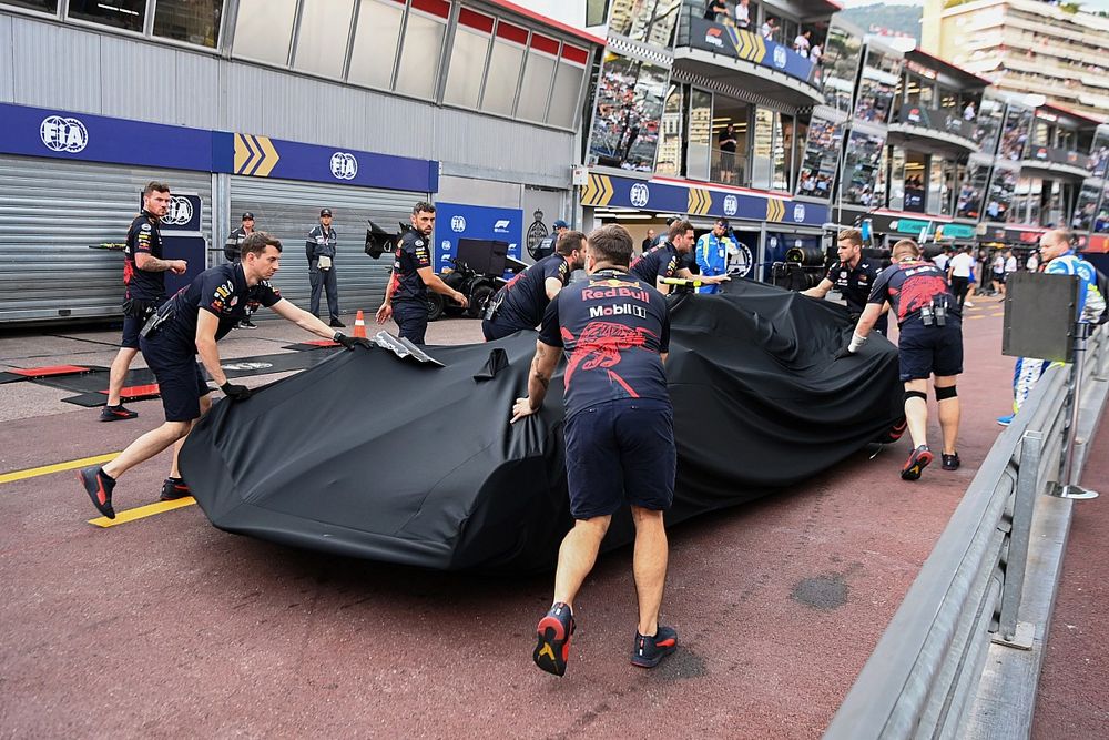 Mecánicos con el coche dañado de Sergio Pérez, Red Bull Racing RB18, bajo una lona