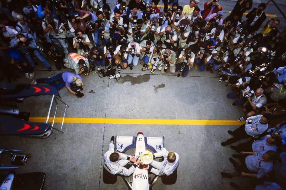 Mika H&auml;kkinen, McLaren MP4-13 Mercedes, and David Coulthard, McLaren MP4-13 Mercedes, celebrate victory in the race and the world championship opposite a bank of photographers