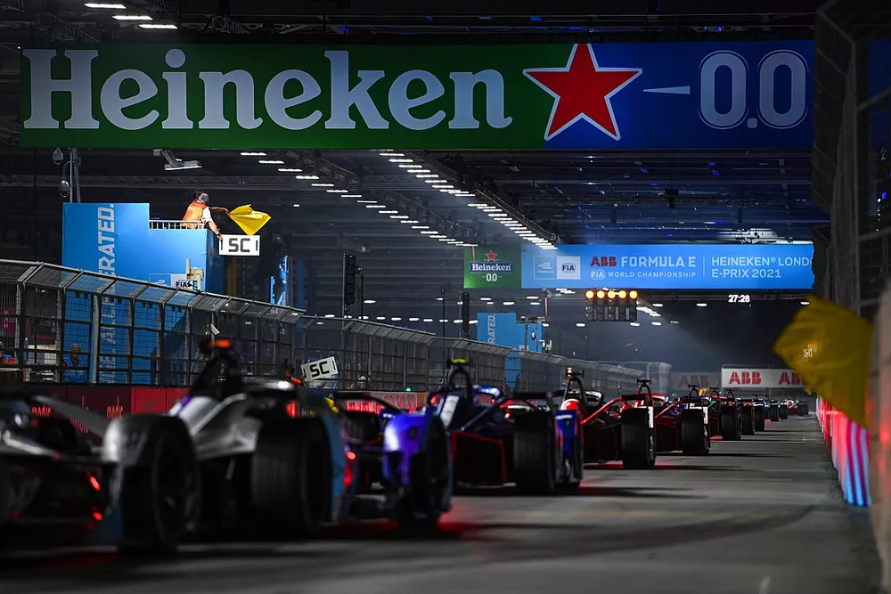 The cars pass the start line as the yellow flags are waved behind the Safety Car