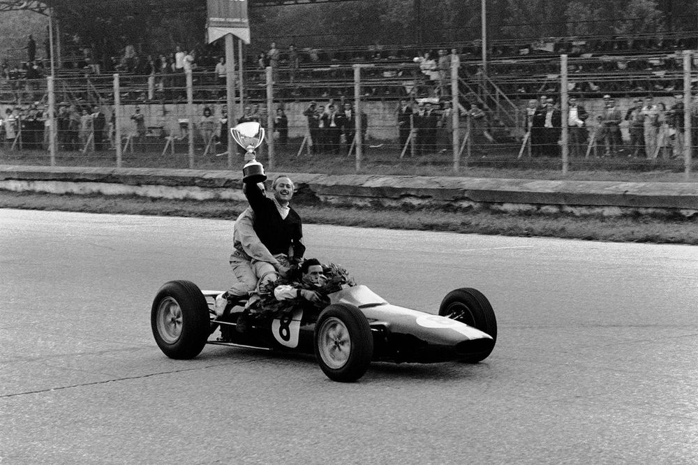 Jim Clark, Lotus 25 Climax le da un impulso al jefe del equipo, Colin Chapman, ya que celebran terminar en la 1ª posición y asegurar los títulos de Campeones del Mundo de pilotos y constructores