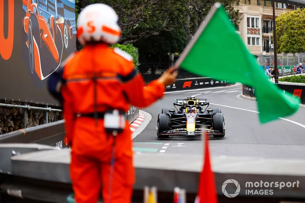 A marshal waves a green flag as Max Verstappen, Red Bull Racing RB20, approaches