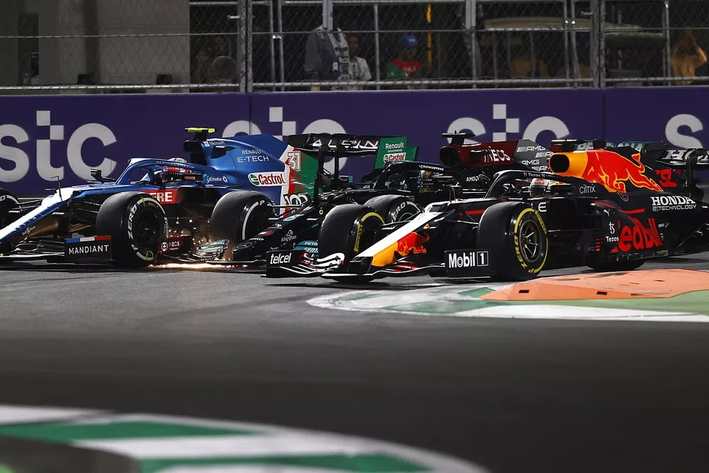 Max Verstappen, Red Bull Racing RB16B, Lewis Hamilton, Mercedes W12, and Esteban Ocon, Alpine A521, battle for the lead at the restart