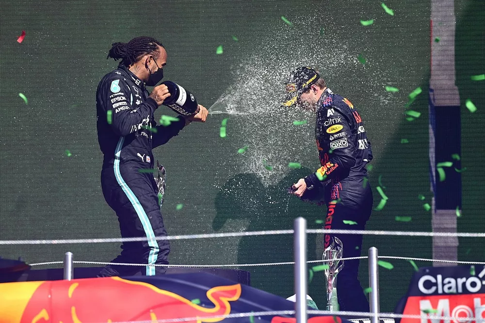 Lewis Hamilton, Mercedes, 1st position, sprays Max Verstappen, Red Bull Racing, 1st position, with Champagne on the podium
