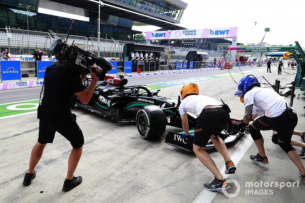 Miembros del equipo de pits de McLaren intentan asistir a Valtteri Bottas, Mercedes W12, despu&eacute;s de que hizo un trompo en el pit lane