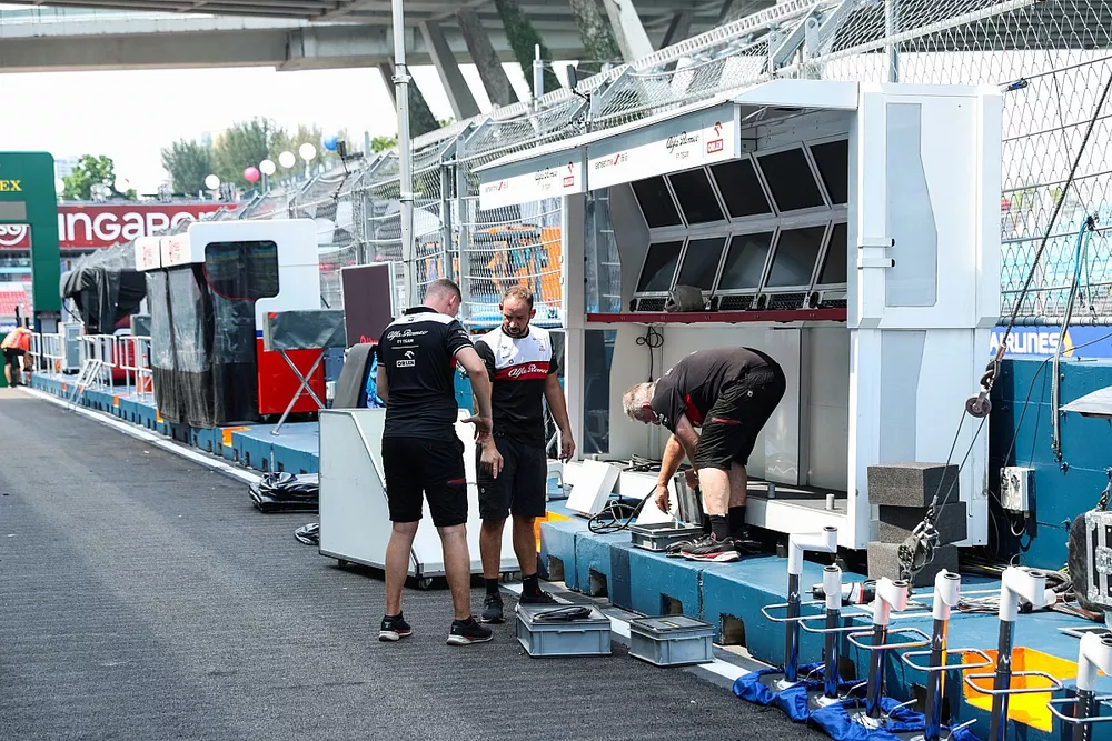 Los mec&aacute;nicos de Alfa Romeo trabajando junto a su puesto en el pit lane