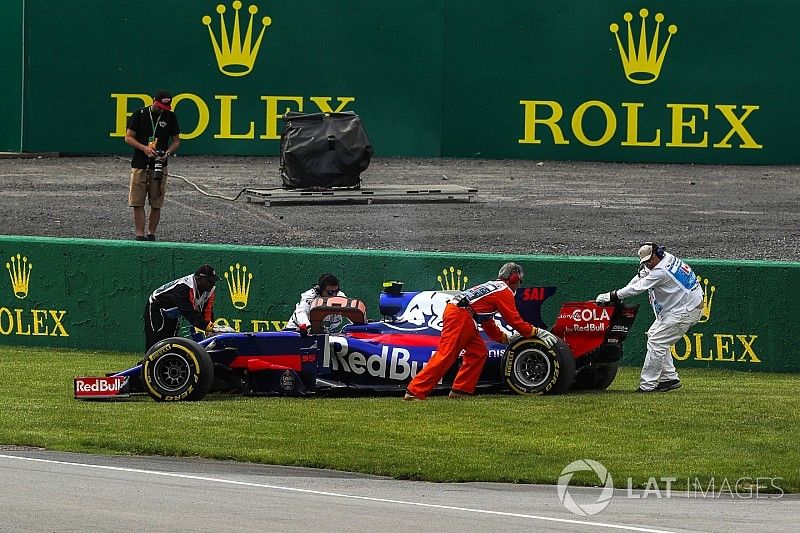 El coche de Carlos Sainz Jr., Scuderia Toro Rosso STR12 es quitado por los oficiales despu&eacute;s de aban