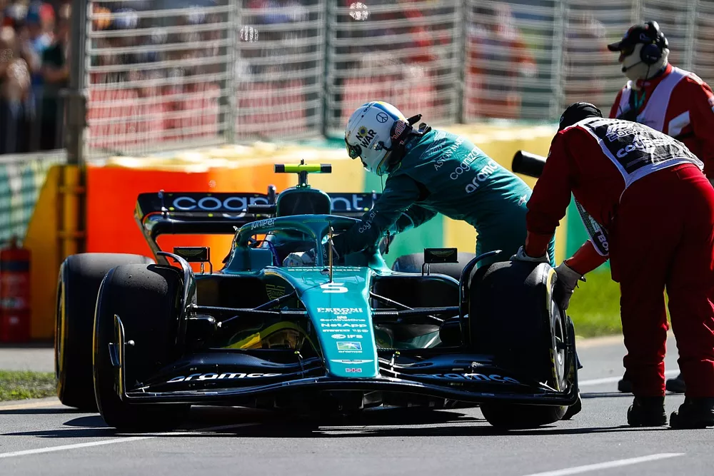 Oficiales de pista asisten a Sebastian Vettel, Aston Martin AMR22, tras abandonar en la FP1