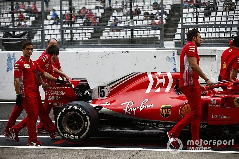 Los ingenieros de Ferrari mueven el auto de Sebastian Vettel, Ferrari SF71H, en el pit lane.