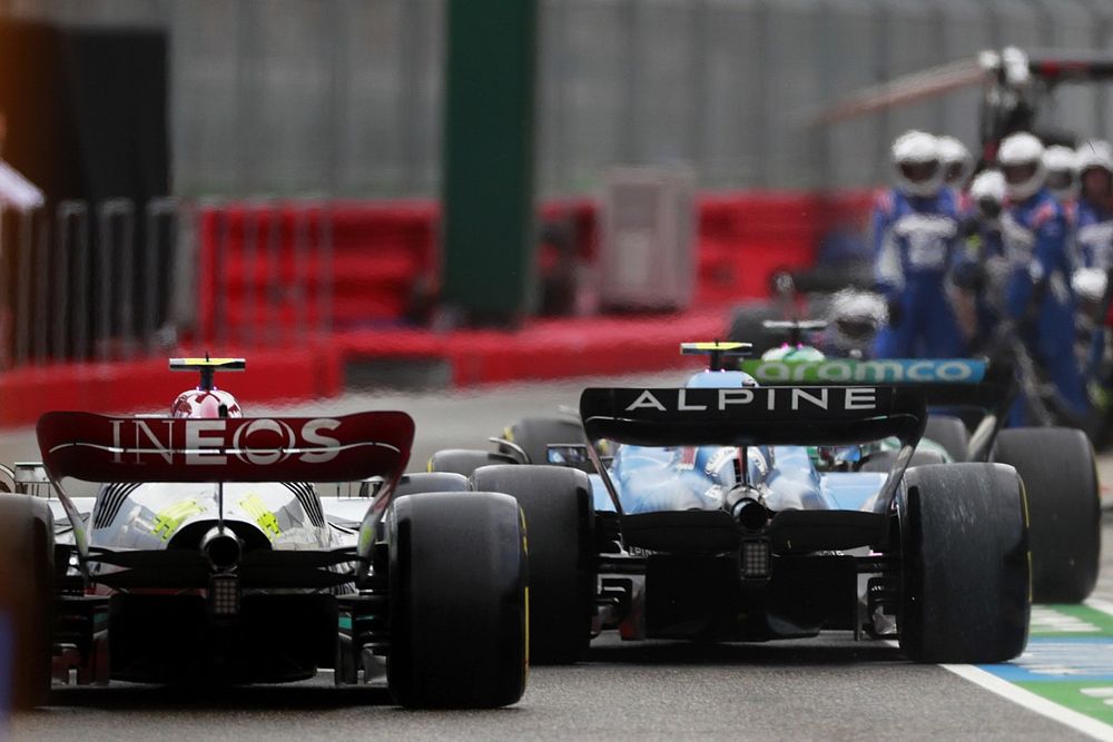 Esteban Ocon, Alpine A522, en la trayectoria de Lewis Hamilton, Mercedes W13, en el pit lane