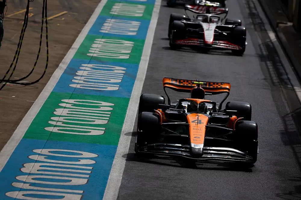 Lando Norris, McLaren MCL60, Nico Hulkenberg, Haas VF-23, in the pit lane