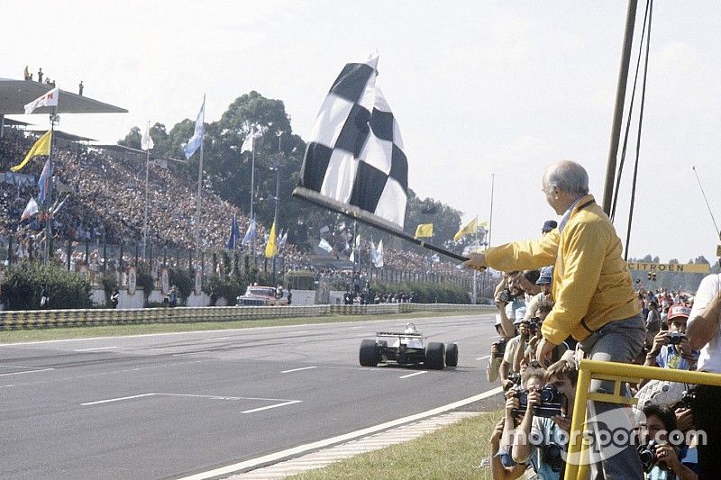 Juan Manuel Fangio shows the chequered flag to Carlos Reutemann, Williams FW07C-Ford Cosworth