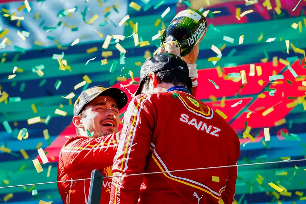 Charles Leclerc, Scuderia Ferrari, 2&ordf; posici&oacute;n, vierte champ&aacute;n sobre Carlos Sainz, Scuderia Ferrari, 1&ordf; posici&oacute;n, en el podio en se&ntilde;al de celebraci&oacute;n.