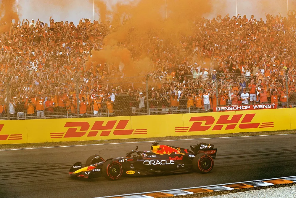 Max Verstappen, Red Bull Racing RB18, 1st position, waves from his cockpit as fans turn the air orange in celebration of victory