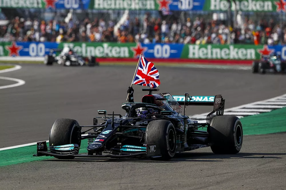 Lewis Hamilton, Mercedes W12, 1st position, waves a Union flag from his cockpit on the way to Parc Ferme