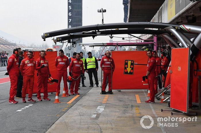 Mecánicos de Ferrari con paneles para tapar su coche de la vista de los curiosos