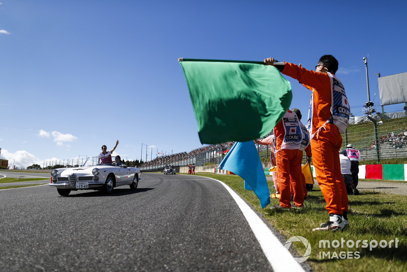 Marshals wave flags as Charles Leclerc, Sauber, passes in the drivers parade