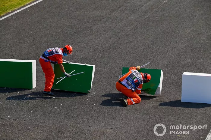 Los oficiales de pista reparan la barrera rota después de que Sebastian Vettel, el Ferrari SF1000 chocó con ella