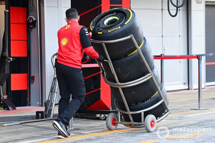 Un mecánico de Ferrari, con una pila de neumáticos por todo el pitlane