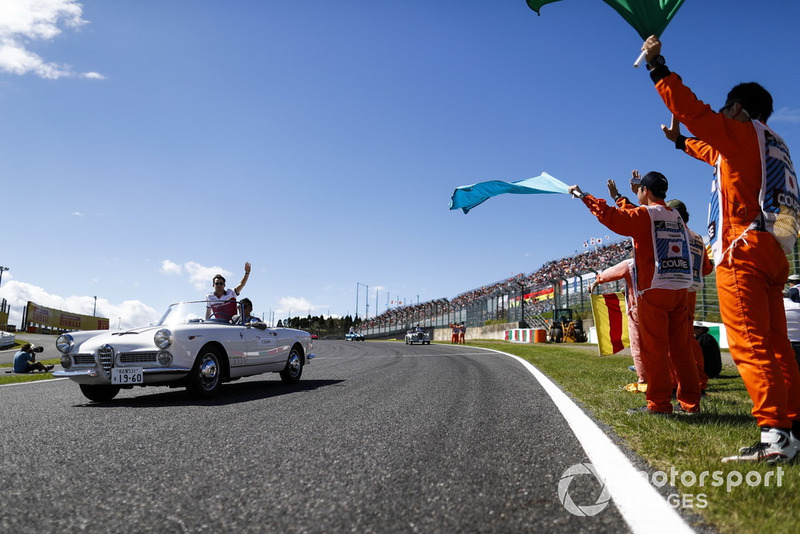 Marshals wave flags as Charles Leclerc, Sauber, passes in the drivers parade