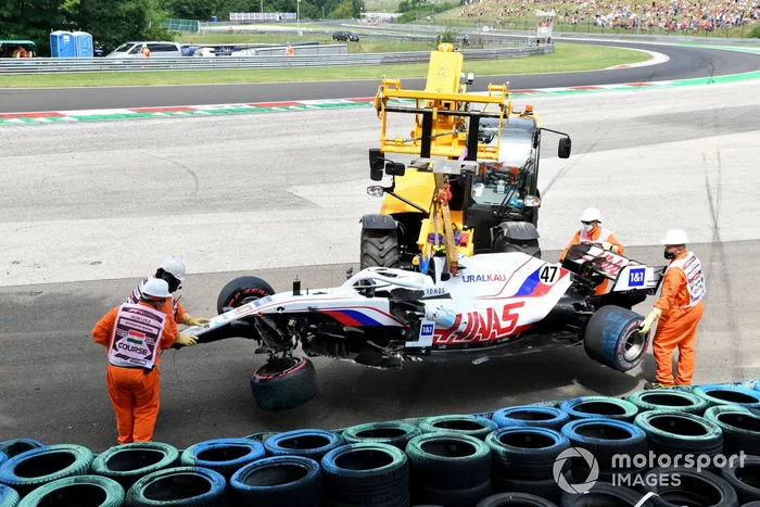 Los oficiales retiran el coche dañado de Mick Schumacher, Haas VF-21, de una barrera de neumáticos tras su accidente en la FP3