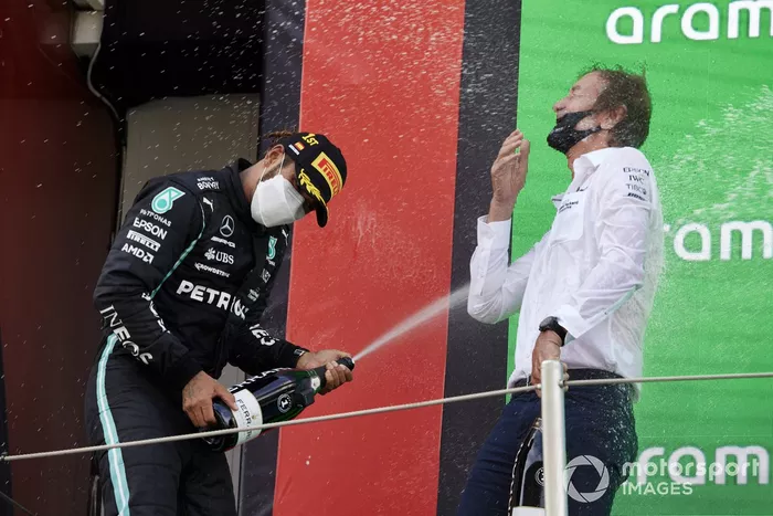 Lewis Hamilton, Mercedes, primera posición, derrama champán a su compañero de equipo en el podio