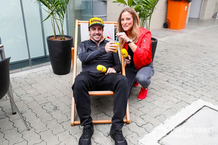 Fernando Alonso, McLaren, toma una bebida mientras está sentado en una tumbona junto a un presentador de RTL