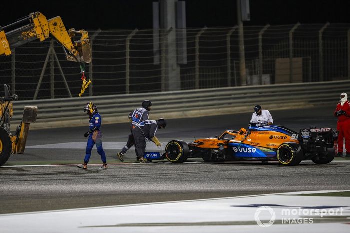 Carlos Sainz Jr., McLaren, se aleja de su coche mientras los oficiales trabajan para retirarlo