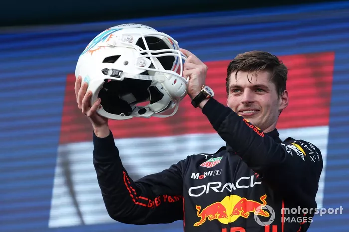 Max Verstappen, Red Bull Racing, 1ª posición, recibe un casco de los Miami Dolphins de la NFL en el podio de manos de la antigua estrella de la NFL Dan Marino.