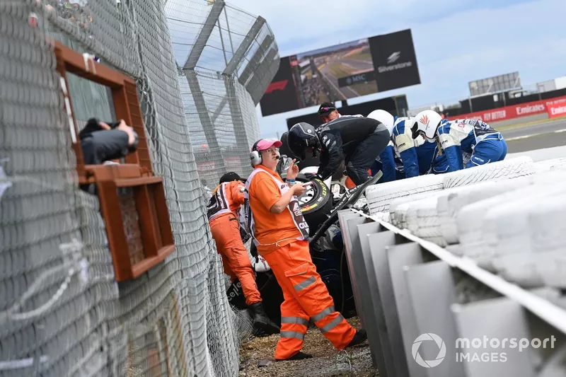 Los oficiales de pista y médicos asisten a Zhou Guanyu, Alfa Romeo C42