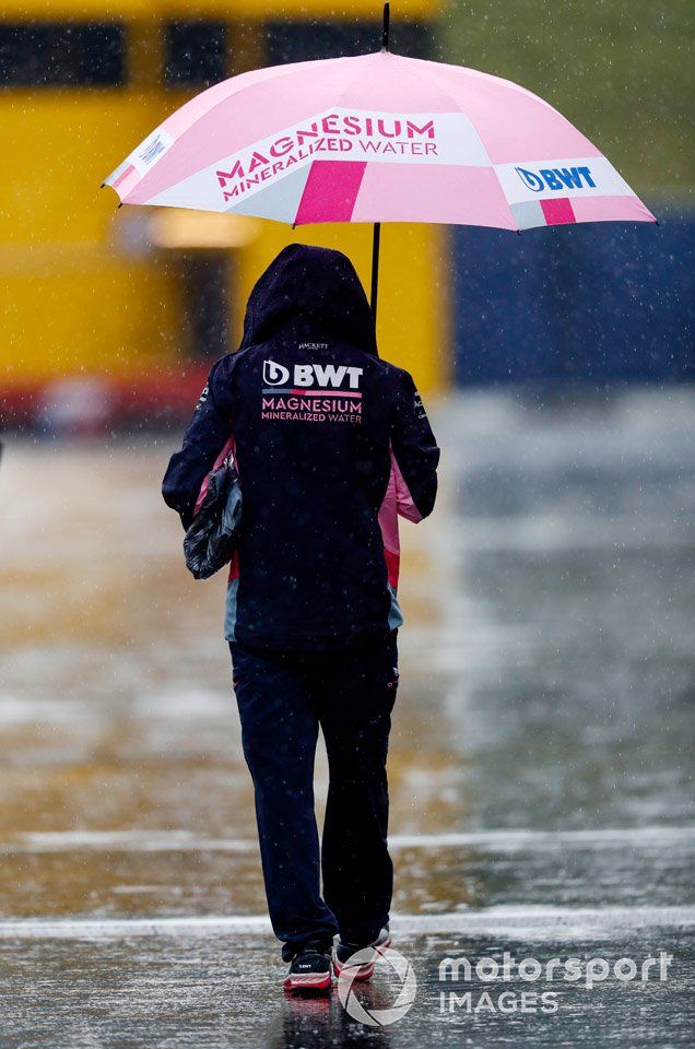 Un miembro de Racing Point llega al circuito con paraguas