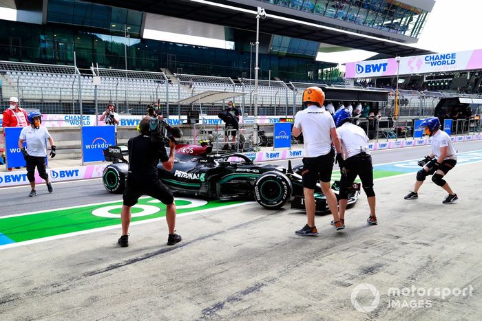 Miembros del equipo de pits de McLaren intentan asistir a Valtteri Bottas, Mercedes W12, después de que hizo un trompo en el pit lane
