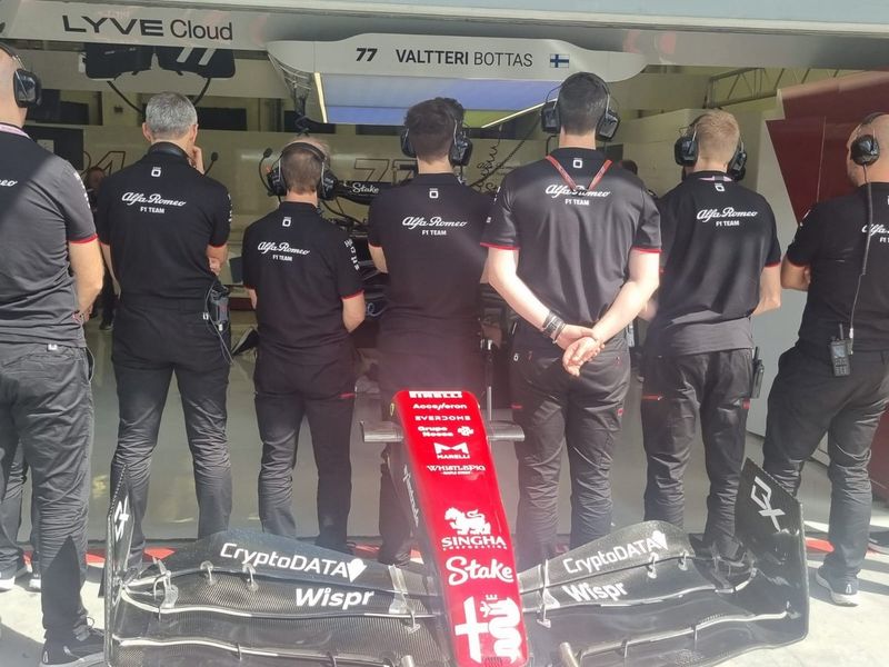 Miembros del equipo Alfa Romeo tapan el coche averiado