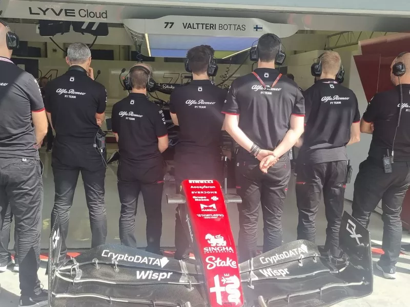 Miembros del equipo Alfa Romeo tapan el coche averiado