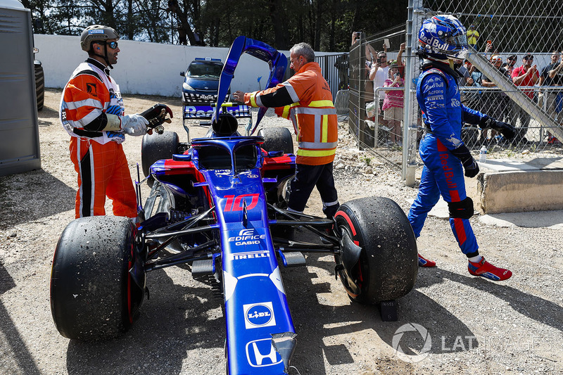 Marshals remove the damaged car of Pierre Gasly, Toro Rosso STR13, as he walks away