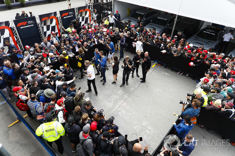 Fernando Alonso, McLaren, Carlos Sainz Jr., Renault Sport F1 Team, and Stoffel Vandoorne, McLaren, sign autographs for fans. Photographers, including Andy Hone, are among the melee in the enclosure