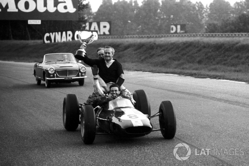 Race winner Jim Clark, Lotus 25 gives Colin Chapman, Lotus Team Owner a lift round the circuit