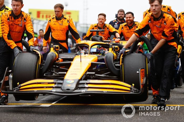 Los mecánicos de McLaren empujan el coche de Oscar Piastri, el McLaren MCL38 hacia su hueco en parrilla