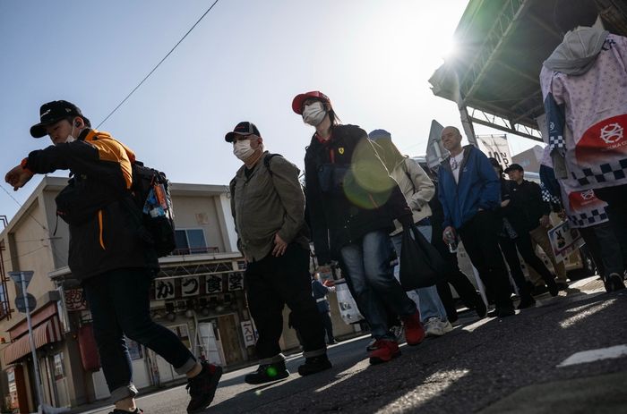 Fans line up near closed shops as they wait for a bus to the race track.