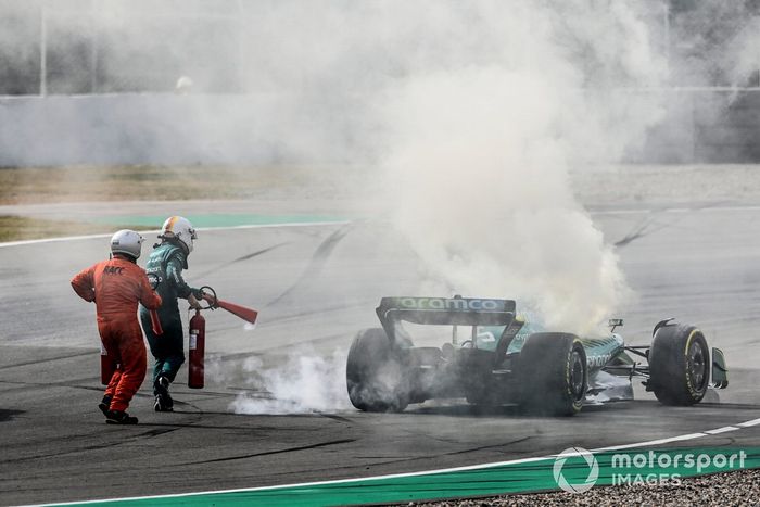 Oficiales de pista asisten a Sebastian Vettel, Aston Martin AMR22, después de que un fallo técnico produzca humo