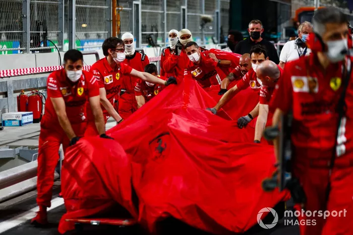 Los mecánicos de Ferrari con el coche dañado de Charles Leclerc, Ferrari SF21, en el pit lane