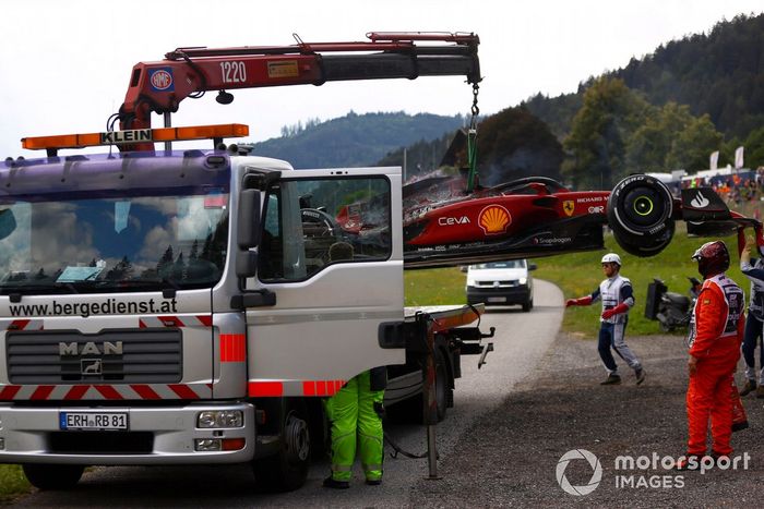 Los oficiales de pista retiran del circuito el coche incendiado de Carlos Sainz, el Ferrari F1-75