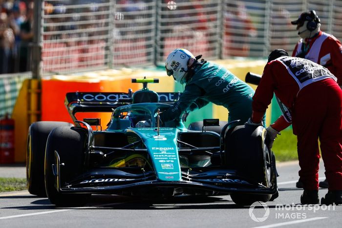 Oficiales de pista asisten a Sebastian Vettel, Aston Martin AMR22, tras abandonar en la FP1